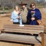 L to R: Jan Petrie, Darryl Johnston and Terri O'Leary stand behind the park bench dedicated to Rusty Woodward.